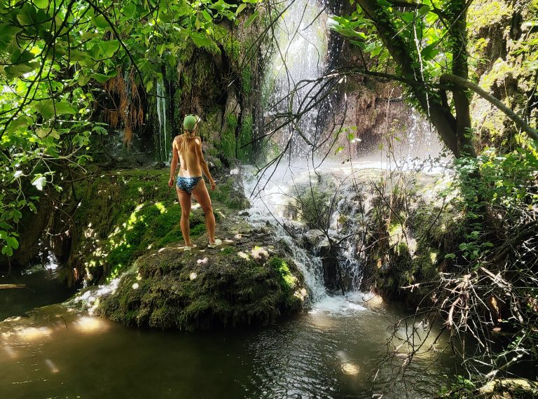 Swimmer on a moss-covered rock by the waterfall of the Gorg de Can Poetí